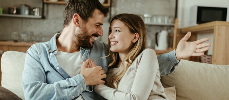 Beautiful Couple Laughing Sit On The Couch At Home