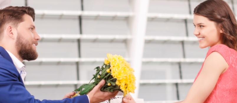 Man offering woman yellow flowers