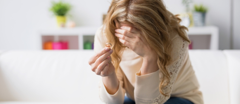 divorcee woman holding her wedding ring and crying