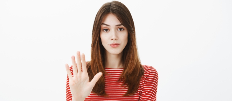Beautiful Girl Showing Her Hand Symbol Of A Stop With A White Solid Background