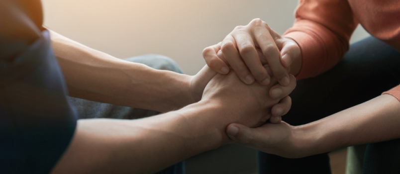 Psychologist Sitting And Touch Hand Young Depressed Asian Man For Encouragement Near Window With Low Light Environment