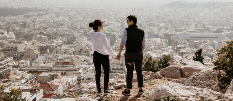 Man And Woman Holding Their Hands Together While Standing On Top Of Cliff