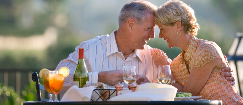 Loving Mature Couple Eating At Outdoor Restaurant Table