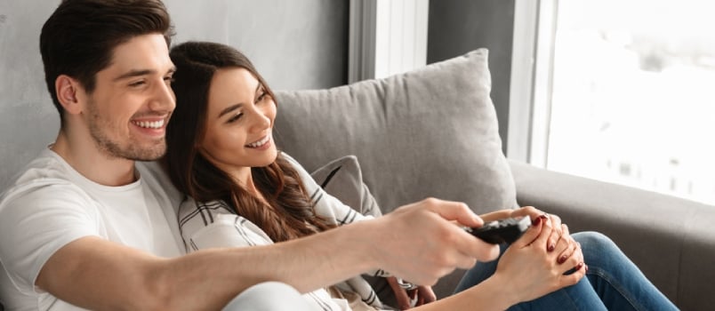 Image Of Happy Man And Woman Sitting On Sofa At Home And Watching Television With Remote Control In Hand