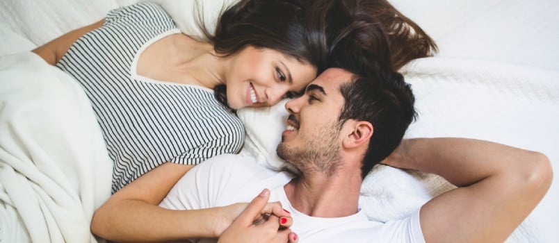 Overhead close up of young couple lying in bed together.