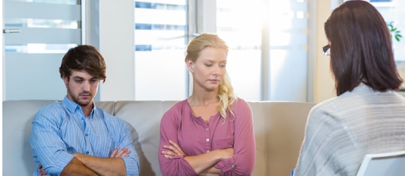 Unsmiling Couple Sitting On The Couch In Therapist Office