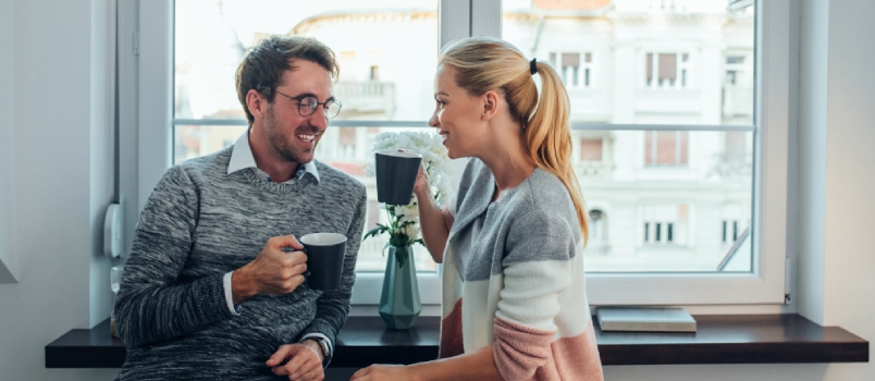 Cheerful Couple Having Coffee Together Behind The Window And Chatting Together With Some Love Moment