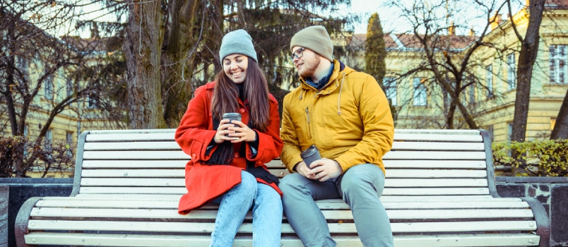 Man Flirting With Woman On The Bench Of City Park In Autumn Day