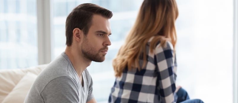Angry Millennial Man Sit On Sofa Not Looking At Beloved Woman, Lost In Thoughts