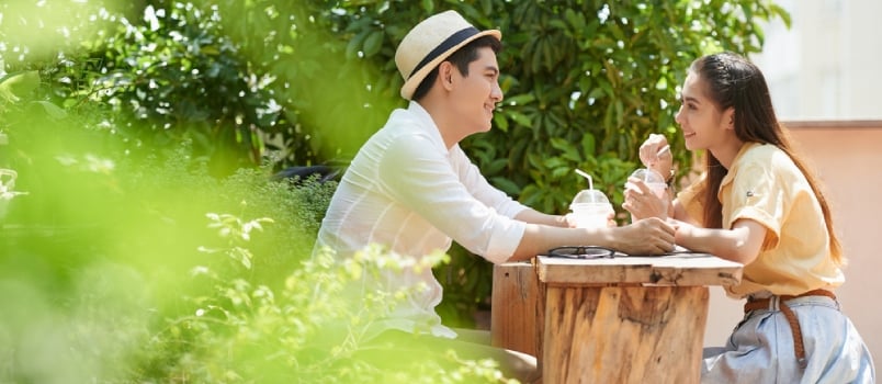 Side View Of Young Couple Sitting In Outdoors Cafe When Having Date