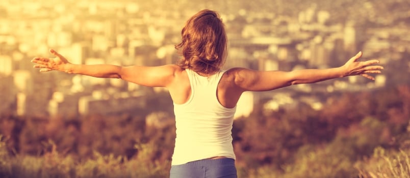Young Woman Spreading Hands Wide Open With City On Background