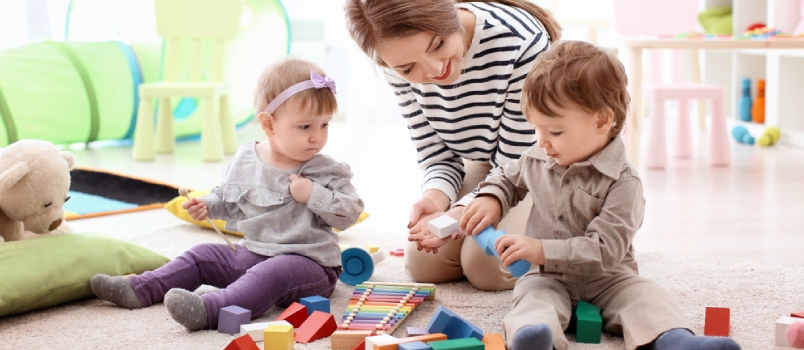 Young Nanny Playing With Little Children, Indoors