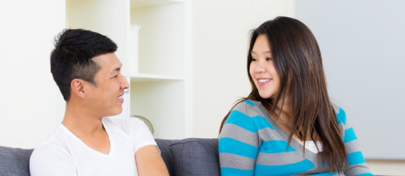 Asian Man And Women Sitting On Couch And Looking Each Other Smiling Love Concept