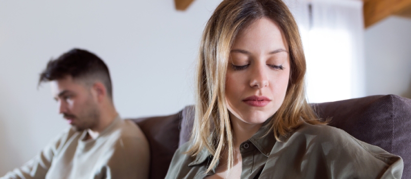Portrait Of Angry Young Couple Sitting On Sofa Together And Looking To Opposite Sides At Home