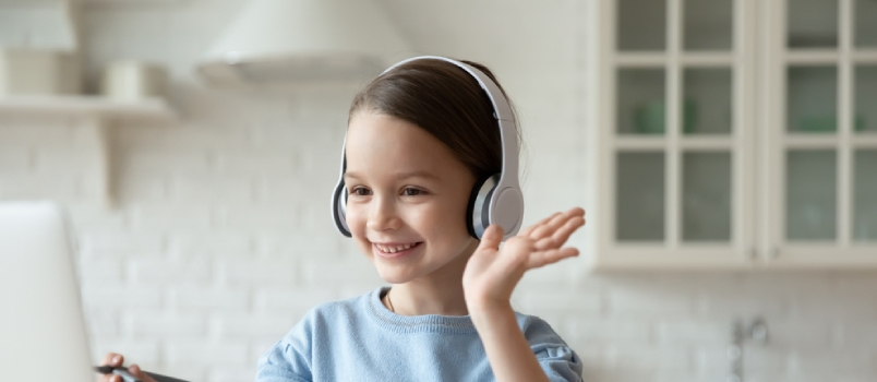 Smiling Little Caucasian Girl In Headphones Have Video Call Distant Class With Teacher Using Laptop