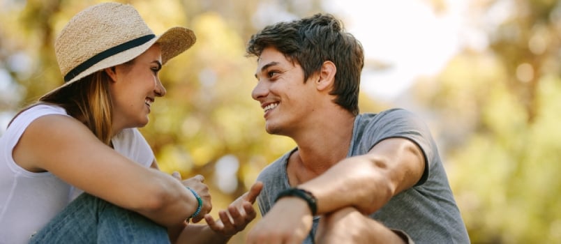 Smiling Couple Sitting Outdoors Looking At Each Other And Talking