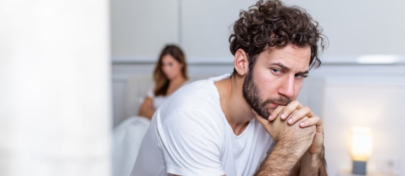 Sad Guy Sitting On Bed,girlfriend In The Background