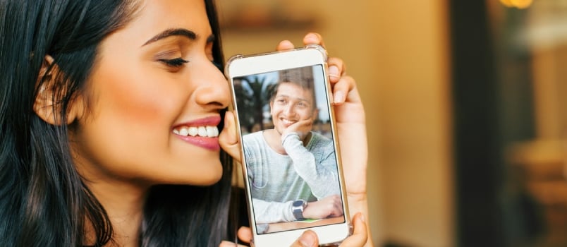 Junge indische Frau, die ihr Telefon mit einem Foto ihres Geliebten hält