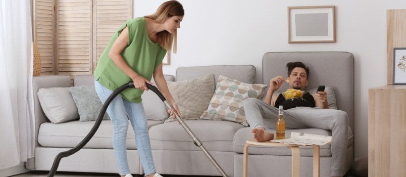 Angry Women Cleaning Floor By Vaccum Cleaner And Husband Lying Behind On Couch Lazy Peoples Concept