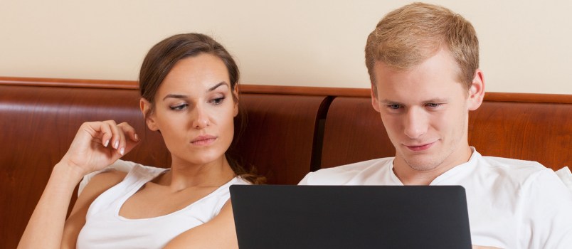 Man And Women At Bedroom On His Bed While Men Working On Laptop Women Looking Him Cross-eyes Ruin Relationship Concept