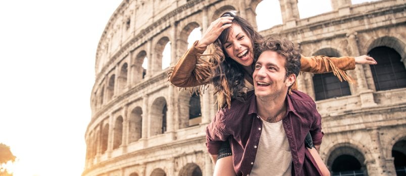 Young Couple At The Colosseum, Rome - Happy Tourists Visiting Italian Famous Landmarks