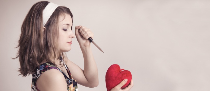 Pretty Pin Up Woman Cutting A Toy Heart With A Knife