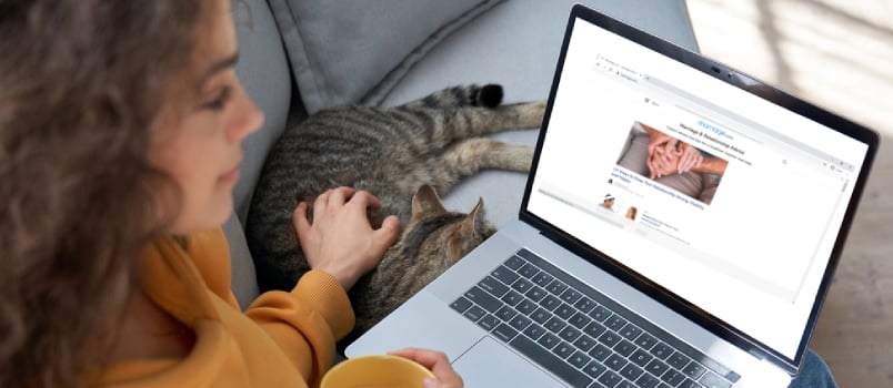 Young Hispanic Latin Teen Girl Student Relax Sit On Sofa With Cat Holding Laptop Looking At Mock Up White Computer Screen Online Learning On Pc