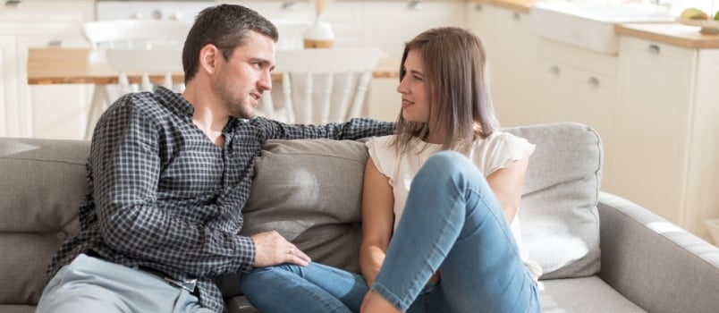 Positive Couple Having Conversation While Resting On Sofa At Home