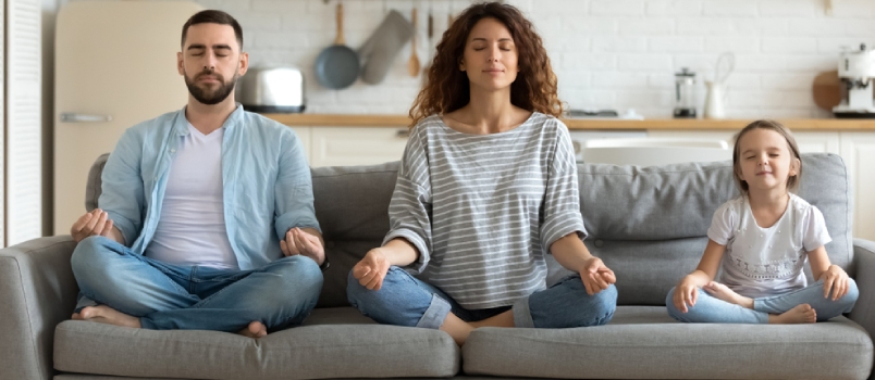 Horizontal Banner Serene Couple And Little Daughter Sitting On Sofa In Lotus Position Closed Eyes Do Meditation Breathing Technique In Living Room
