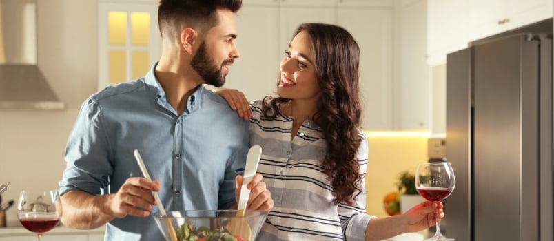 Lovely Young Couple Cooking Salad Together In Kitchen