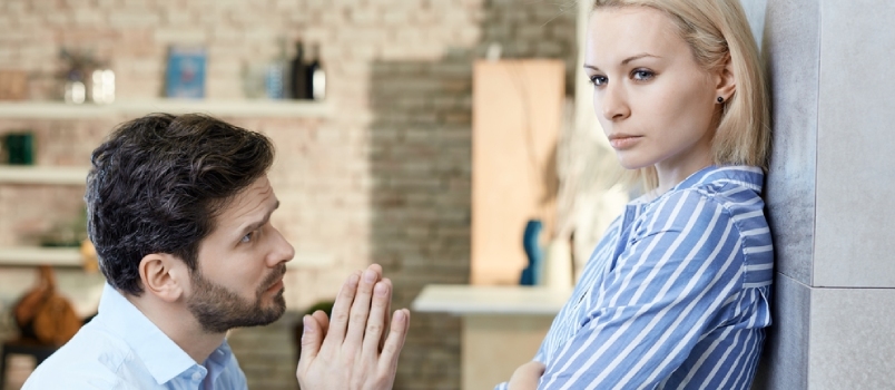 Young Man Asking Sulky Girlfriend's Forgivenes At Home On Bended Knees