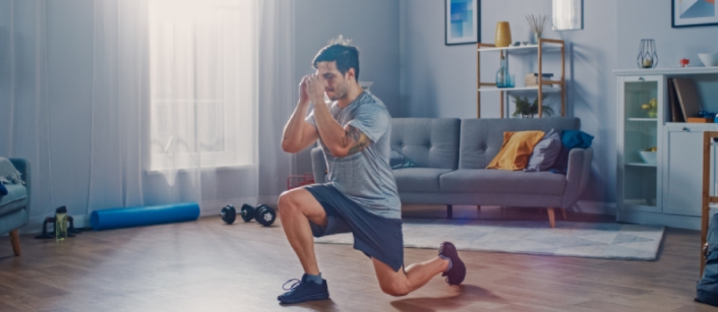 Strong Athletic Fit Man In T-shirt And Shorts Is Doing Forward Lunge Exercises At Home