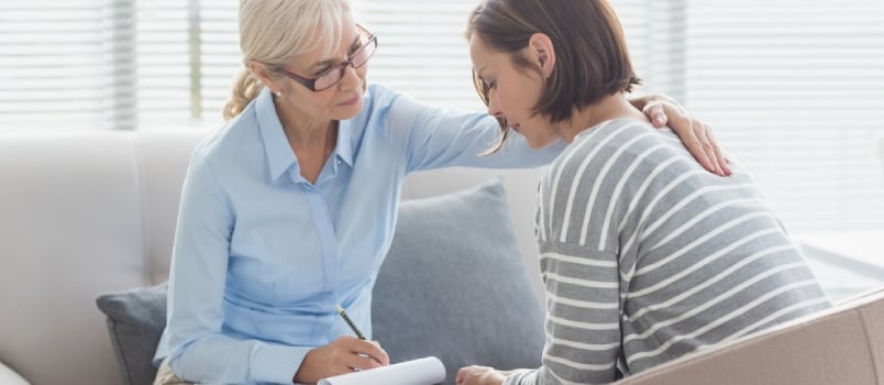 Therapist Comforting Woman On Sofa At Home