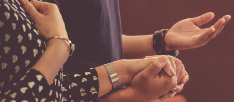 A Couple Holding Hands Praying