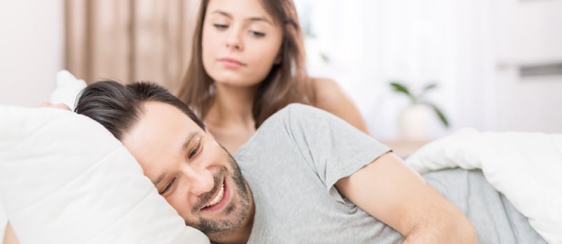 A Young Couple Lying In Bed. One Of Them Use The Phone And Flirting
