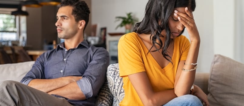 Middle Eastern Young Couple Sitting On Couch After A Fight. Sad Indian Woman Sitting With Hand On Head After Quarrel With Boyfriend At Home