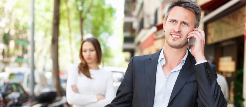 Young Man During Serious Telephone Conversation On Background Of Disappointed Girl