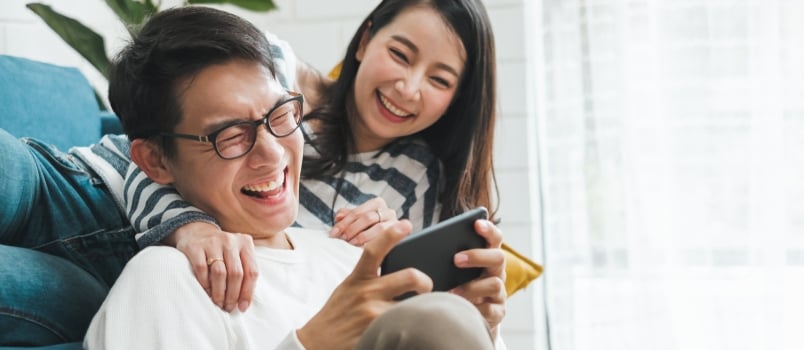 Men And Women Watching Funny Video On Mobile Phone And Laughter Laughing Together