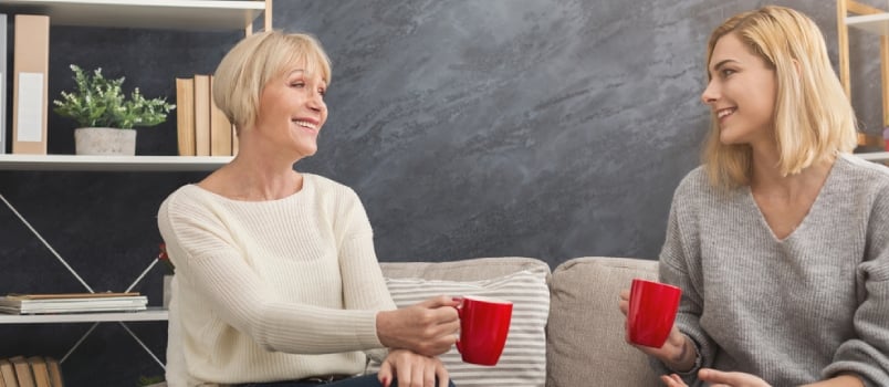 Happy Adult Mother And Daughter Spending Time Together, Chatting, Sharing News And Drinking Coffee At Home On Weekend