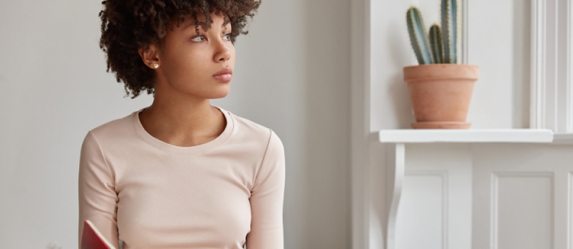Cropped Shot Of Dark Skinned Woman Sits Crossed Legs Looking Away