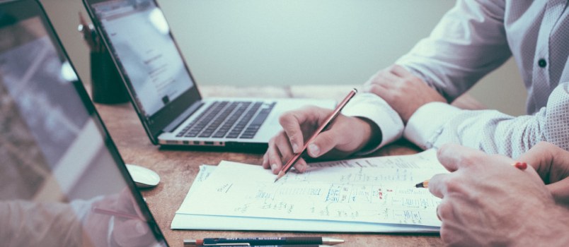 Mens Close Hand Shot With Laptops and Pen With Paper Calculating Something