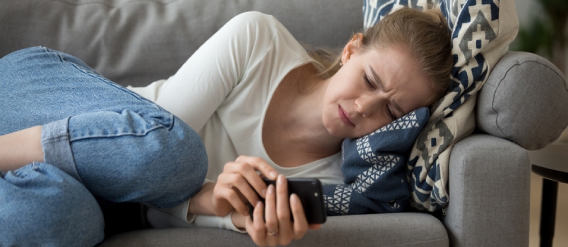 Upset Worried Young Woman Crying Lying On Couch Holding Phone Waiting For Call Message Looking At Smartphone