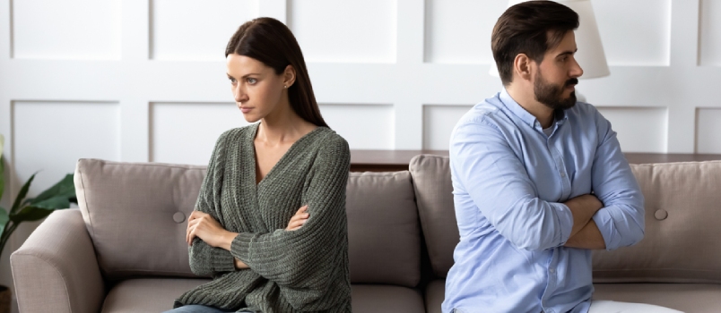 Stubborn Angry Man and Woman Spouses Sit Separate on Sofa at Home Ignore Each Other Avoid Talking After Fight