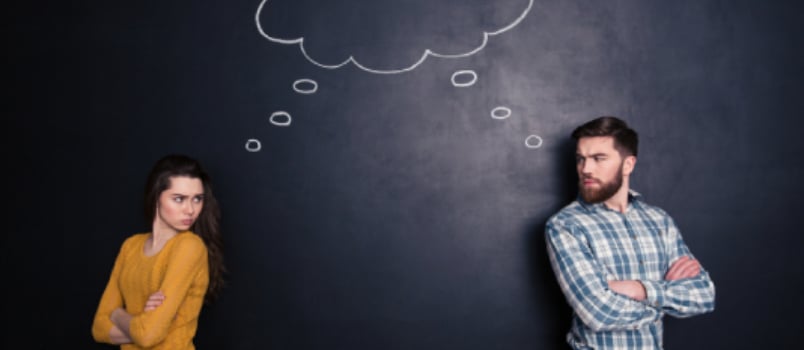 Frowning Angry Young Couple Standing With Hands Folded And Thinking Identically Over Background Of Chalkboard