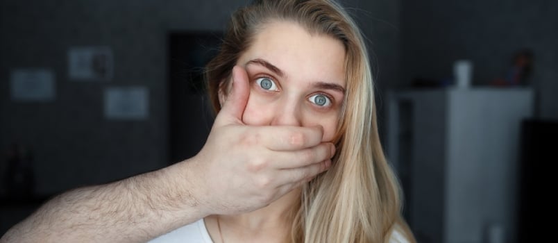 Close-up of a Man's Hand Covering the Mouth of a Young Beautiful Girl or Woman. Concept of Domestic Violence or Kidnapping