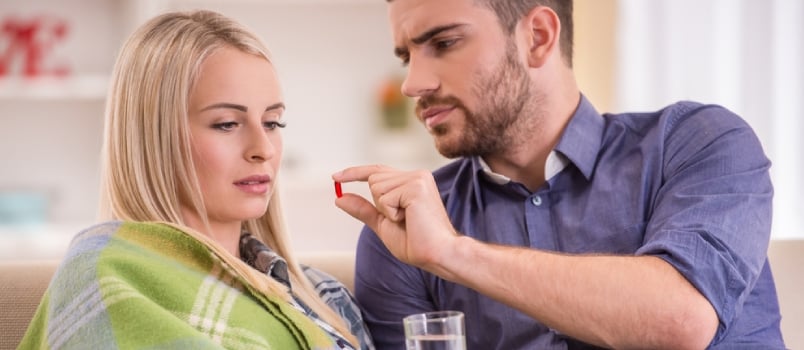 A Man Helps a Sick Girl Sitting on the Couch at Home