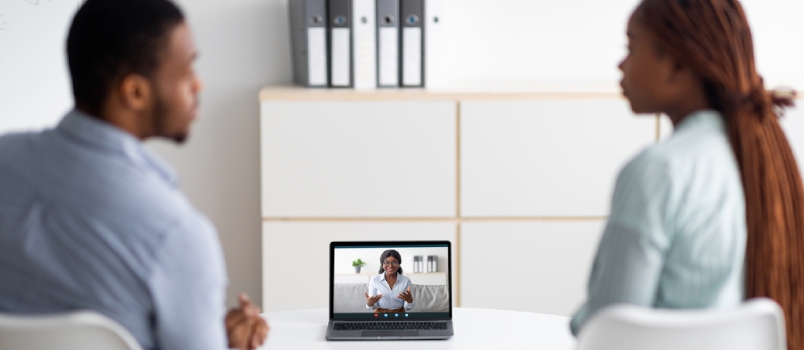 Back View of Young Black Couple Having Online Consultation With Psychotherapist, Using Laptop Computer to Speak to Marriage Counselor Indoors