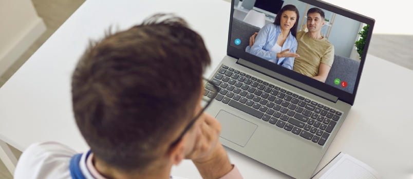 Shoulder View Doctor Therapist Psychologist Speaks With Couple Video Chat Using a Laptop in a Clinic Office