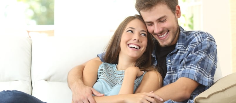 Happy Loving Men and Women Smiling and Sitting on the Couch at Living Room