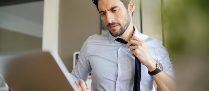 Relaxed Attractive Businessman Undoing Tie and Working in Modern Office